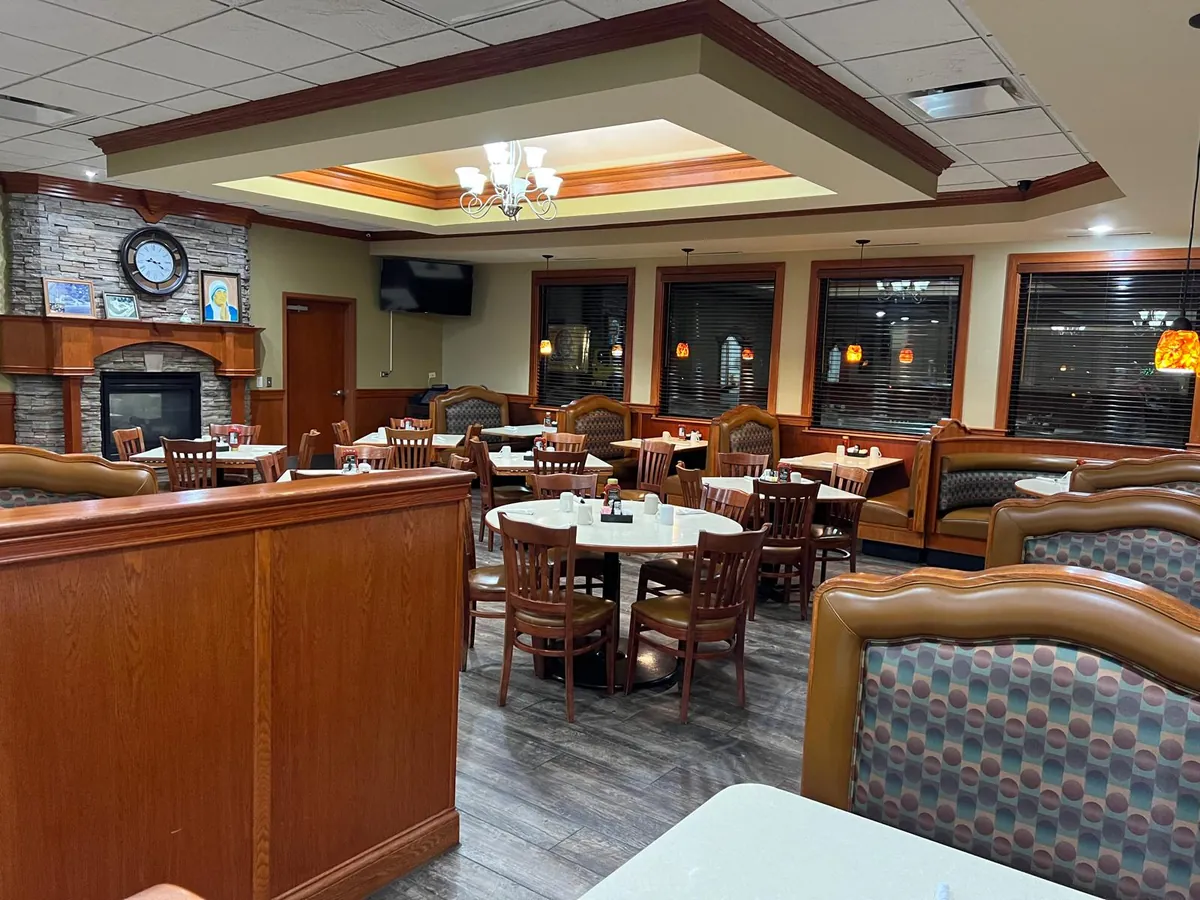 A dining area with a stone fireplace, mantel clock and booths